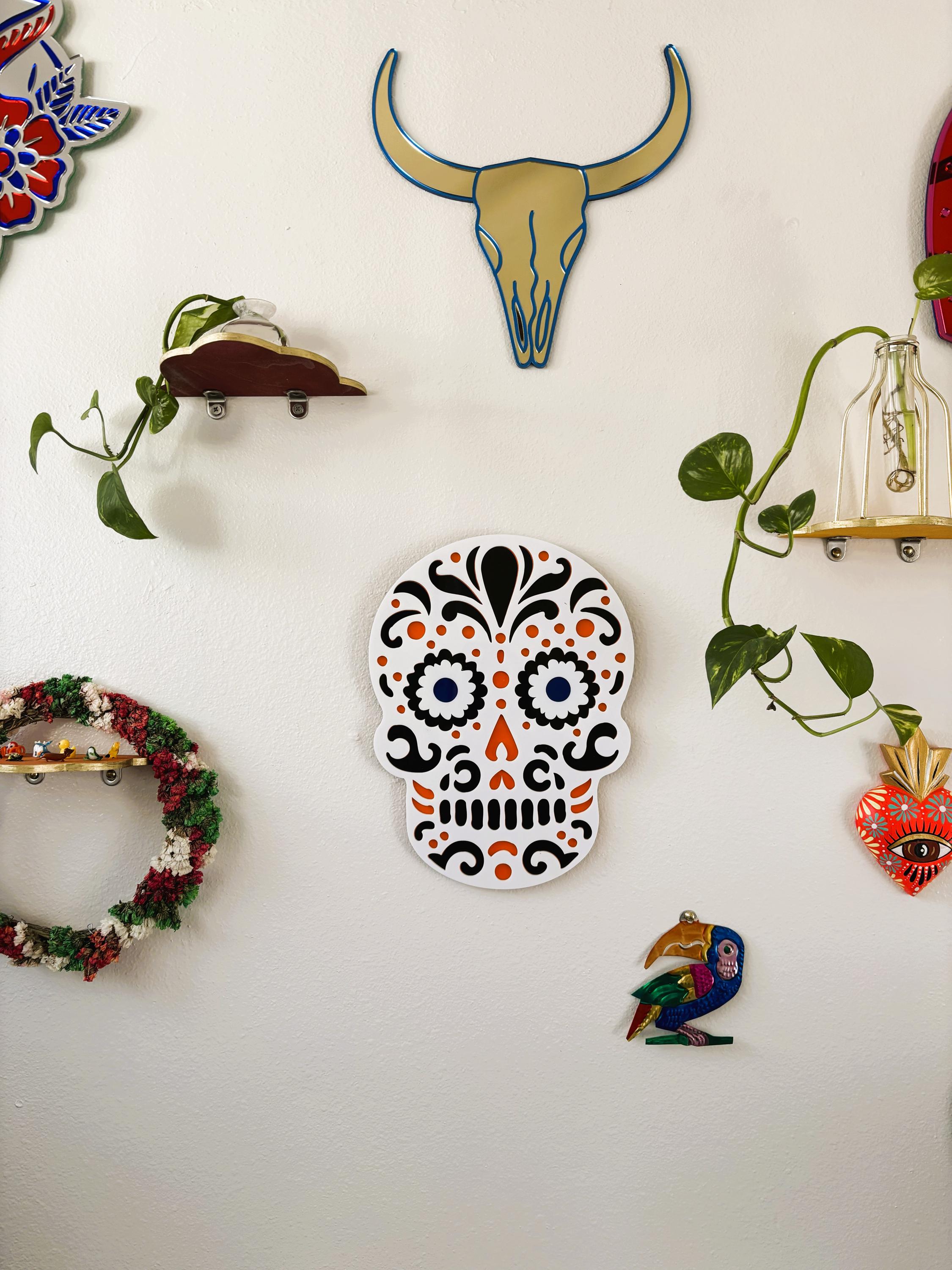 Decorative wall art including a colorful skull, bull skull, and other decorative elements on a white wall.