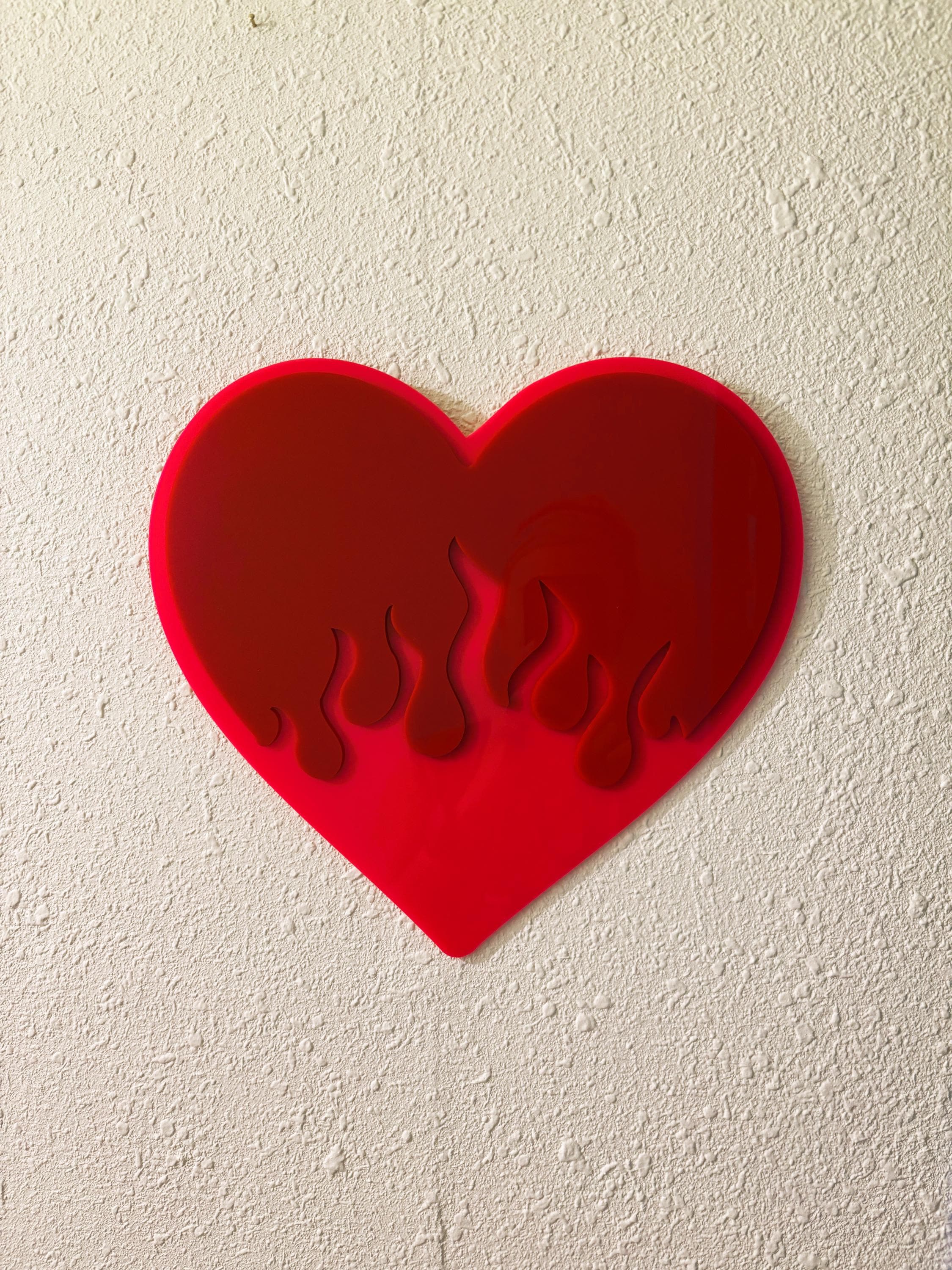 Red heart-shaped object with flame design on a beige wall