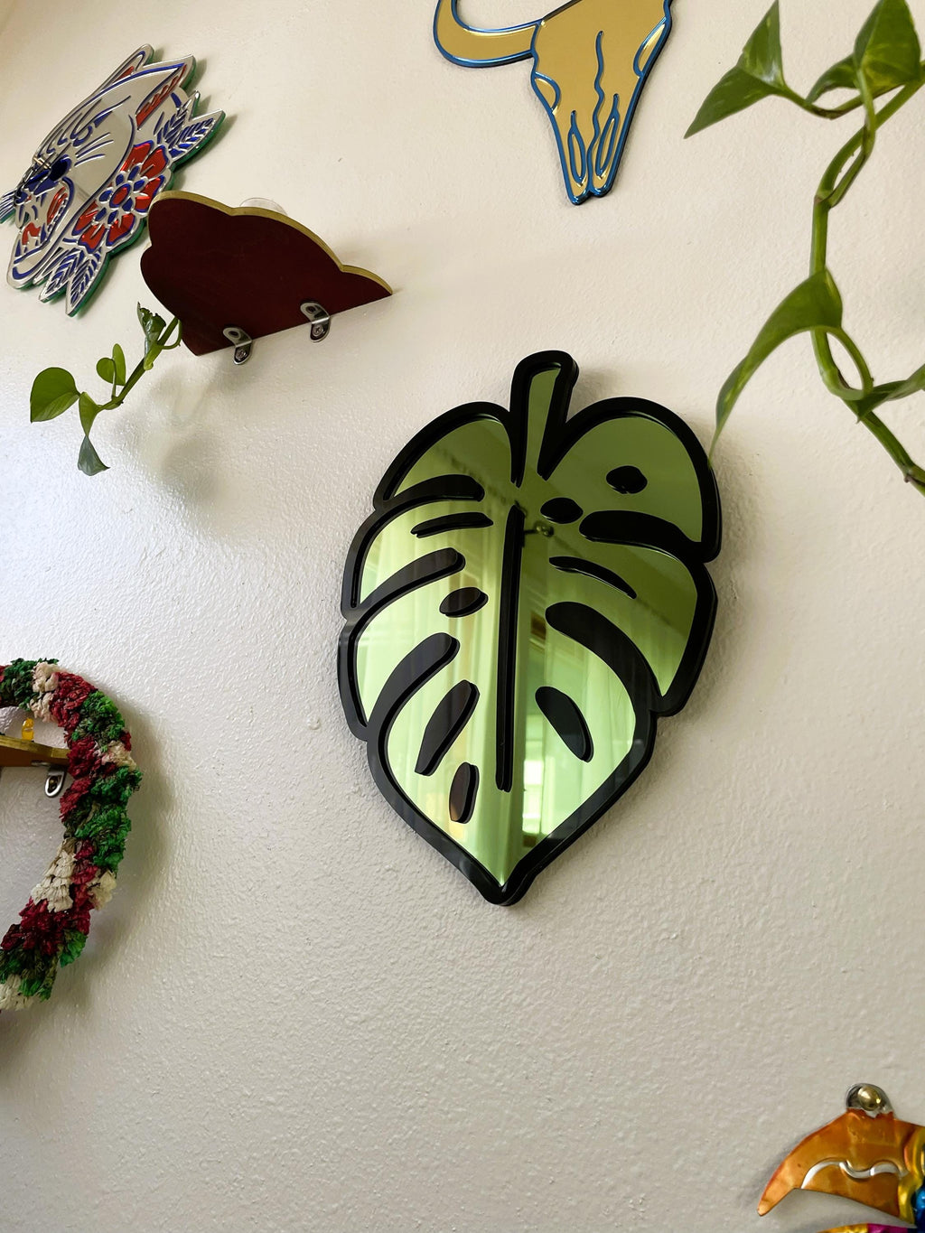 Decorative leaf-shaped object on a white wall with other decorative items.