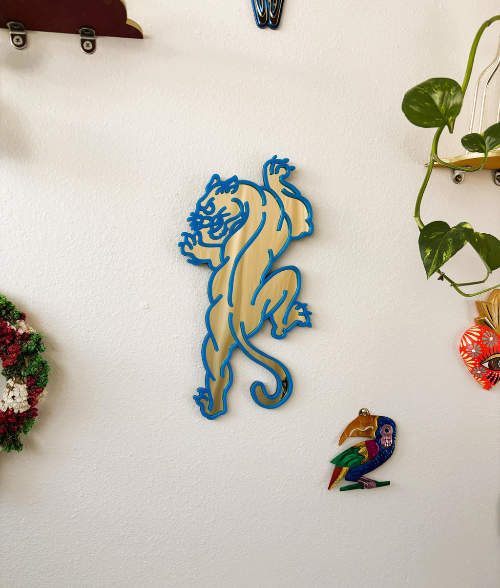 Decorative wall art of a panther on a white wall with other decorative items.