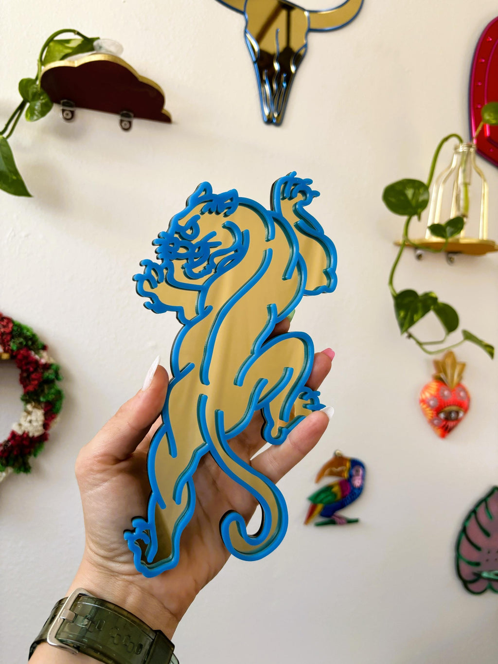 Hand holding a blue and gold lion-shaped object against a decorative wall.