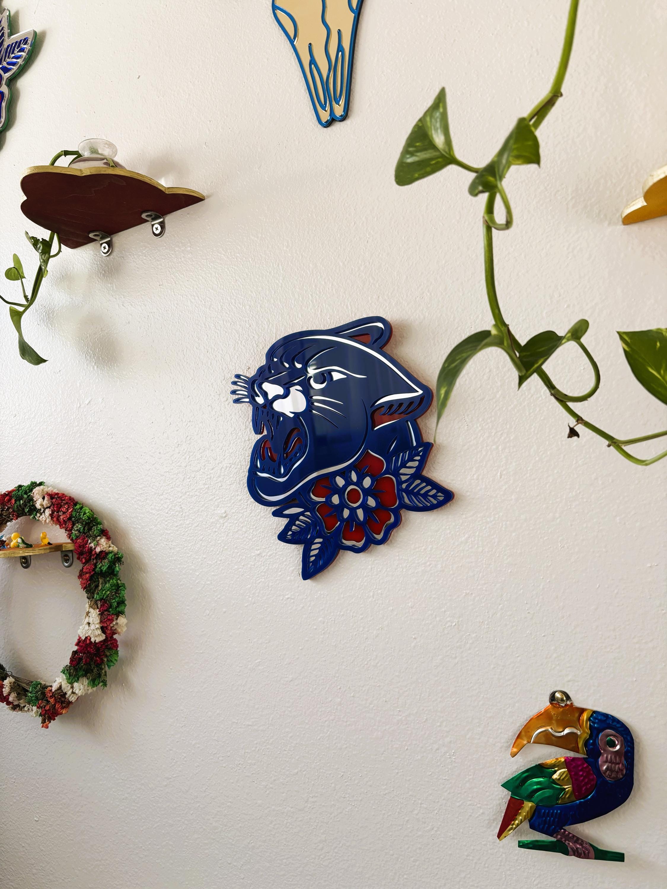 Decorative wall art pieces including a blue panther head, colorful wreath, and bird on a white background with green vines.