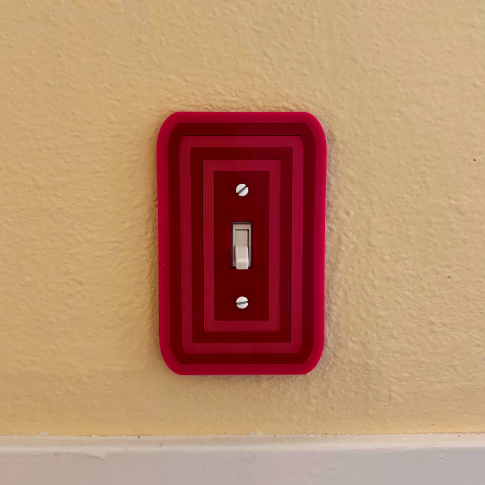 Red decorative light switch cover on a beige wall