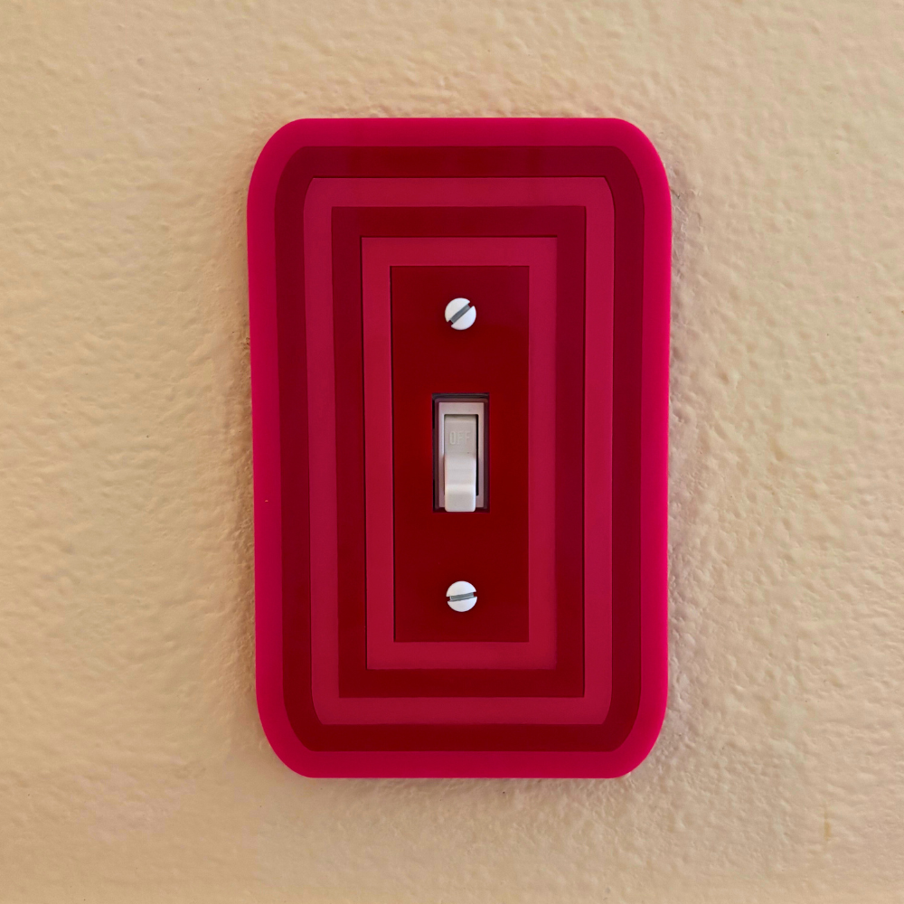 Red decorative wall plate with a silver switch on a beige background