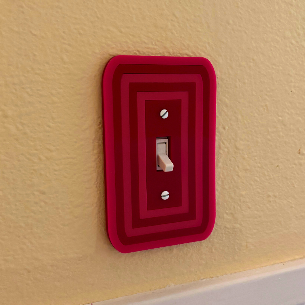Red decorative light switch cover on a beige wall