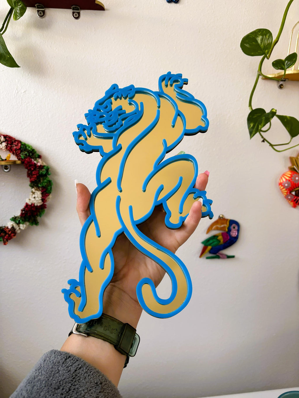 Hand holding a blue and yellow tiger-shaped object against a neutral background