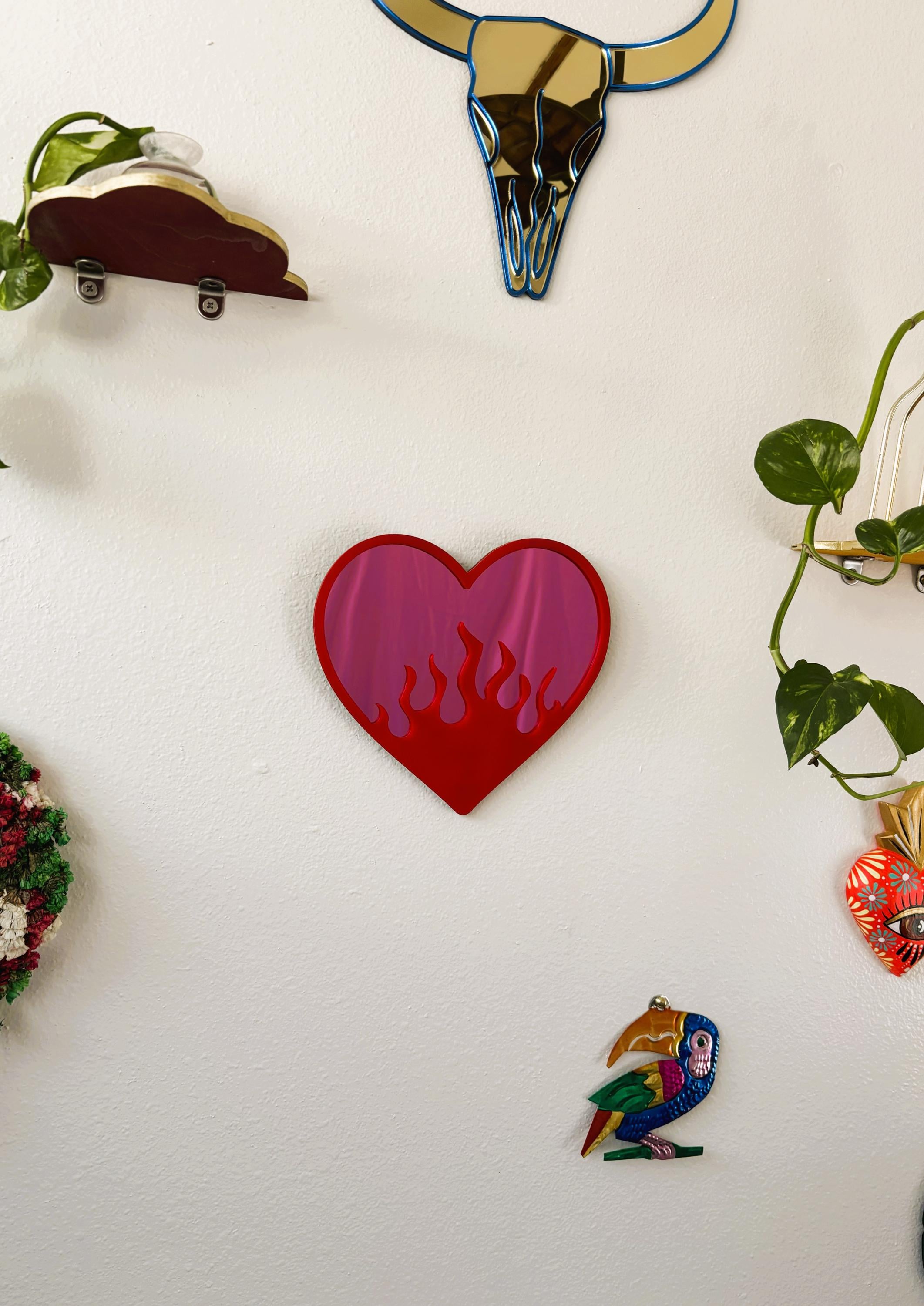 Heart-shaped object with flame design on a white surface surrounded by other decorative items.