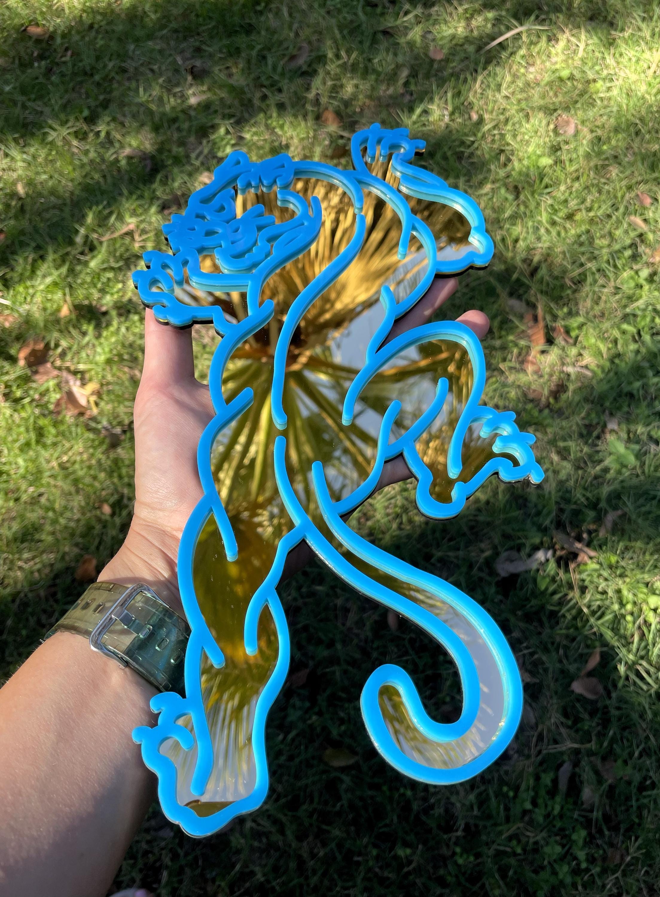 Blue metal dragon sculpture held by a person against a grassy background