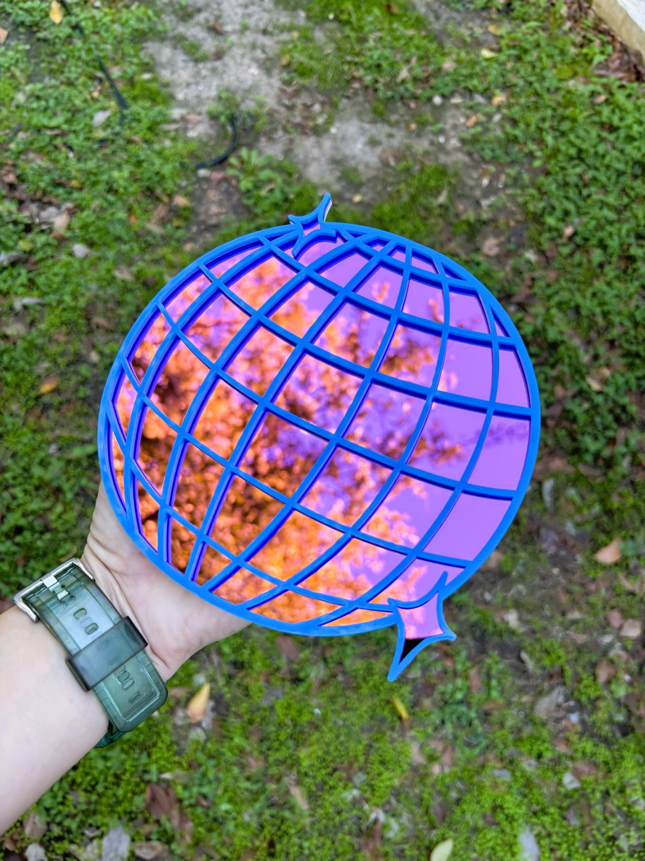 Blue and purple light bulb held by a hand on a grassy background