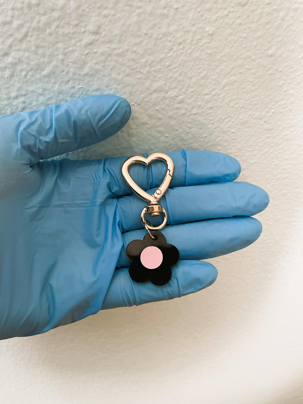 Keychain with heart-shaped clasp held by a gloved hand on a light background