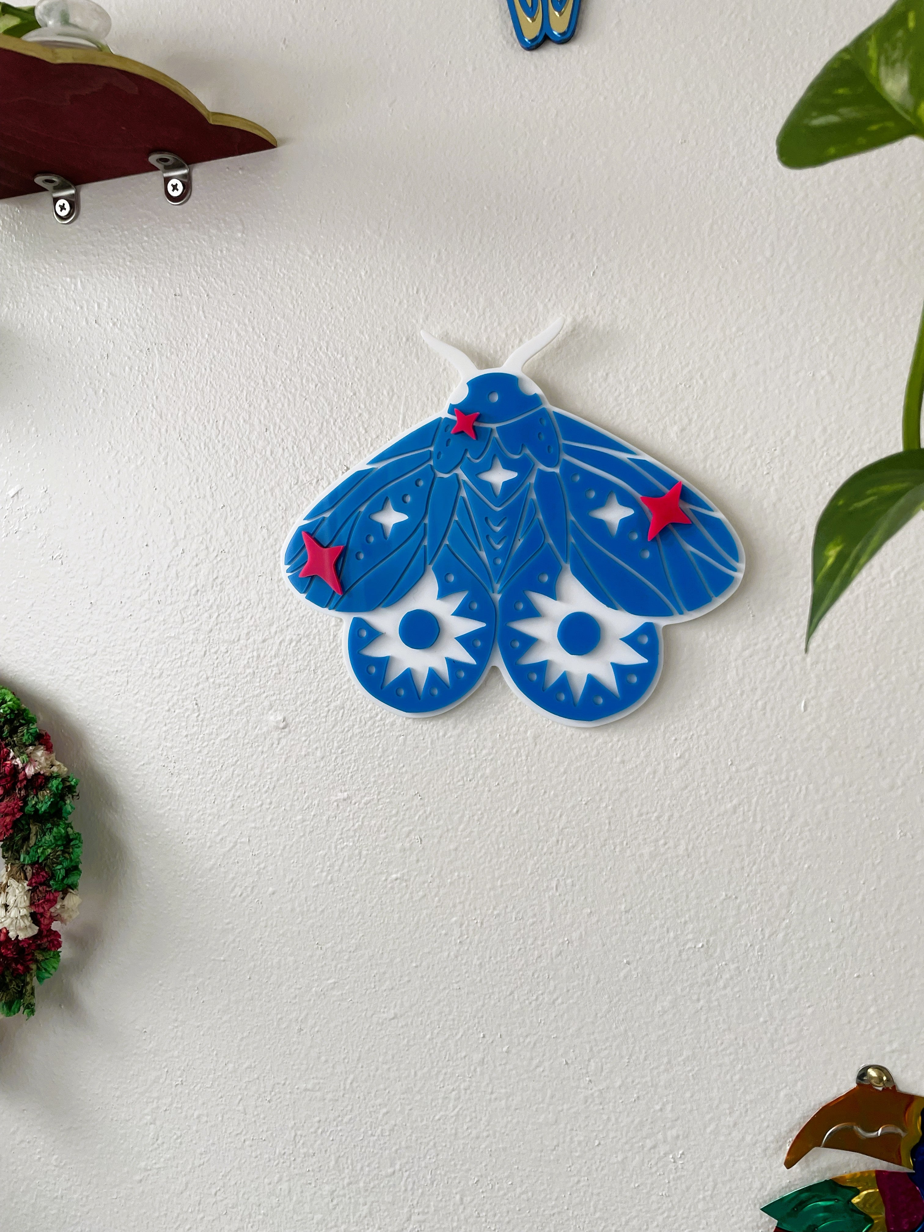 Blue butterfly-shaped object on a white wall with decorative elements.