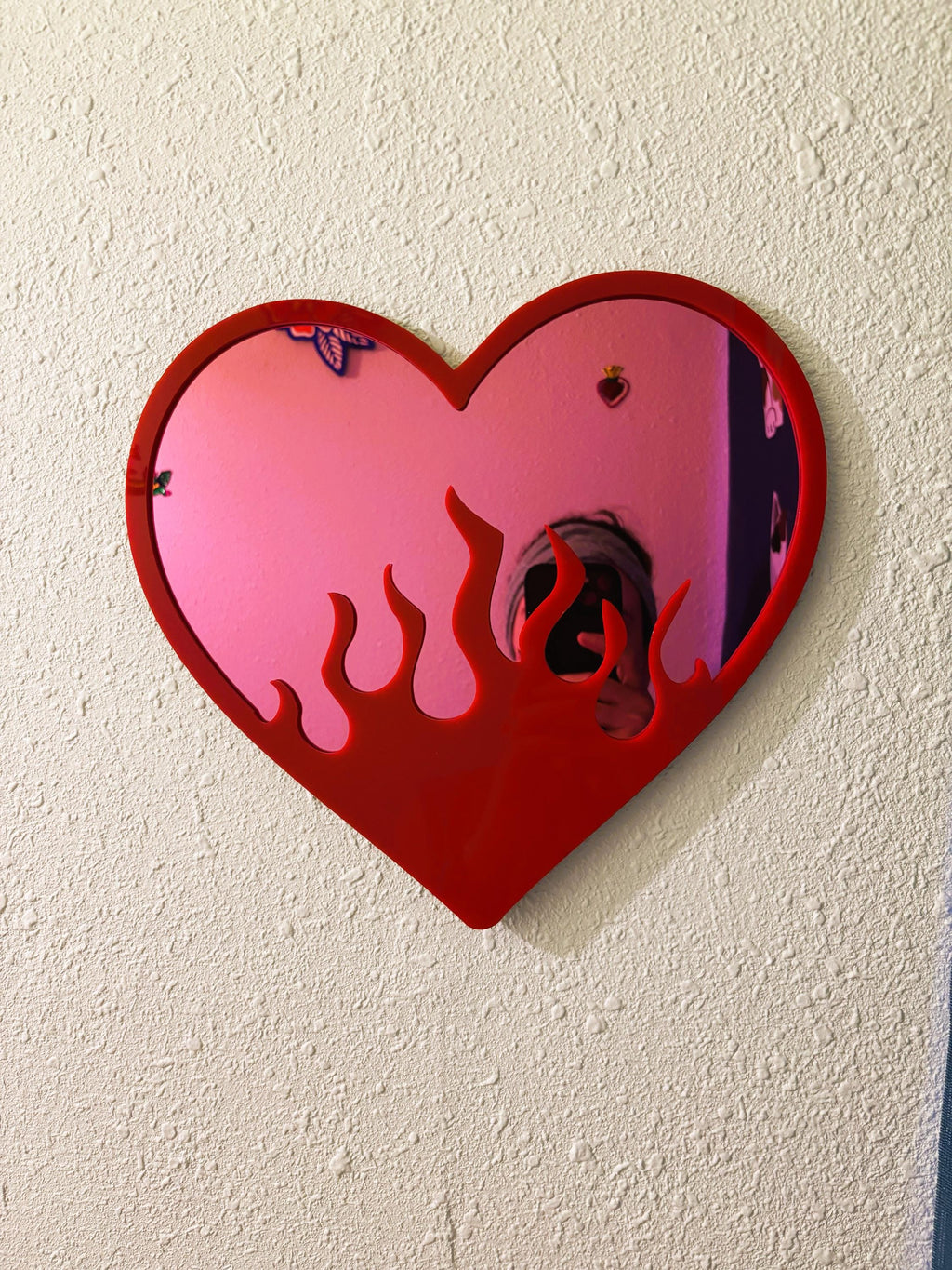 Heart-shaped mirror with pink and red design on a white wall
