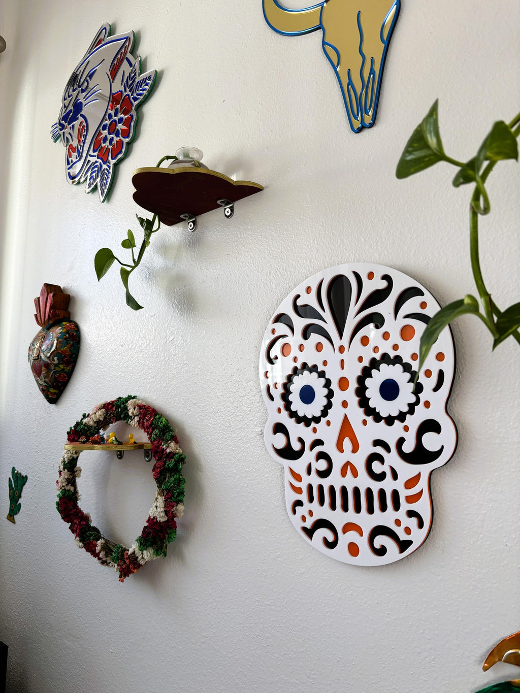 Decorative wall art including a skull design and other colorful pieces on a white wall.