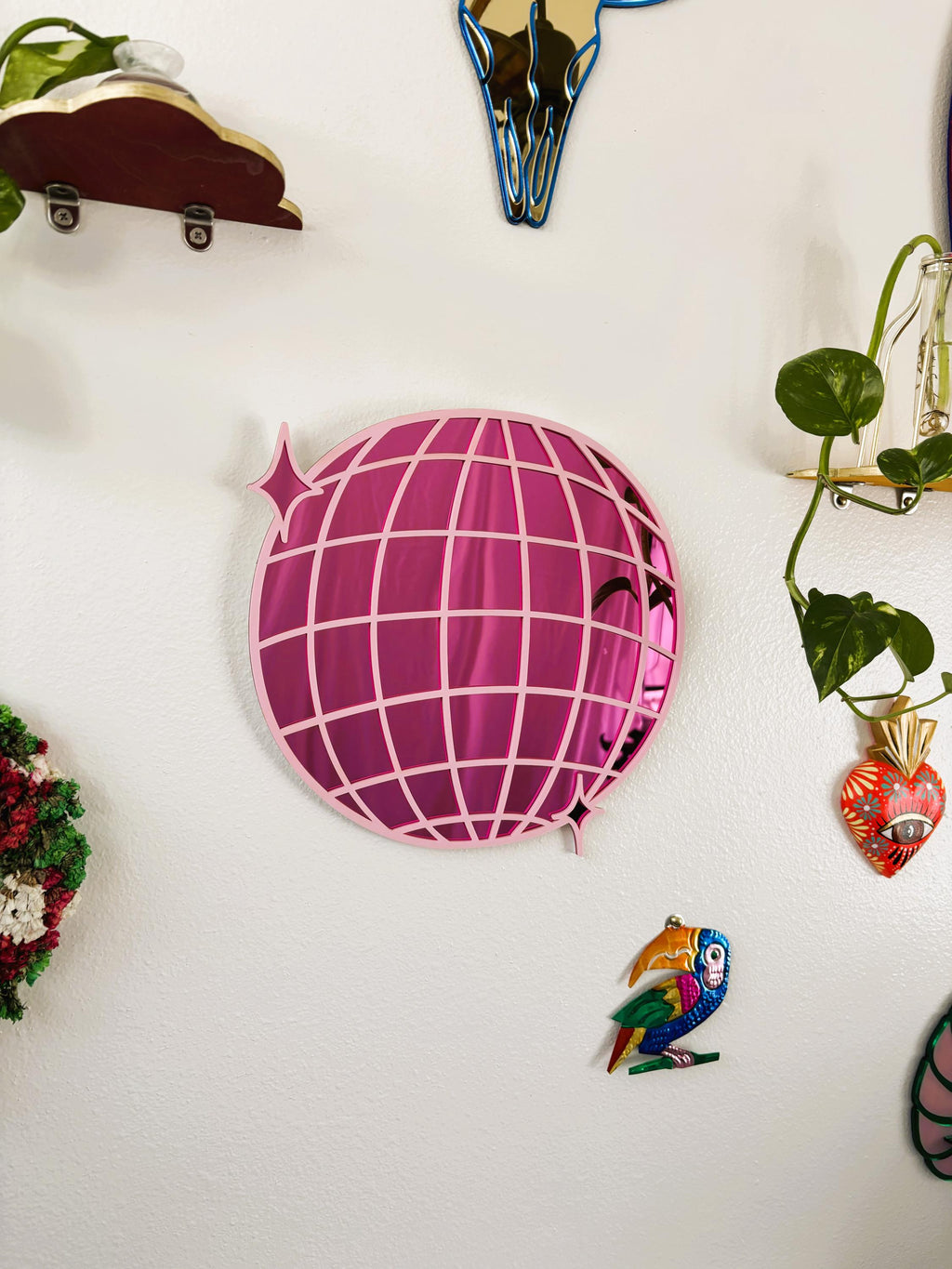 Decorative items including a pink globe-shaped object, a colorful parrot figurine, and a small plant on a white surface.