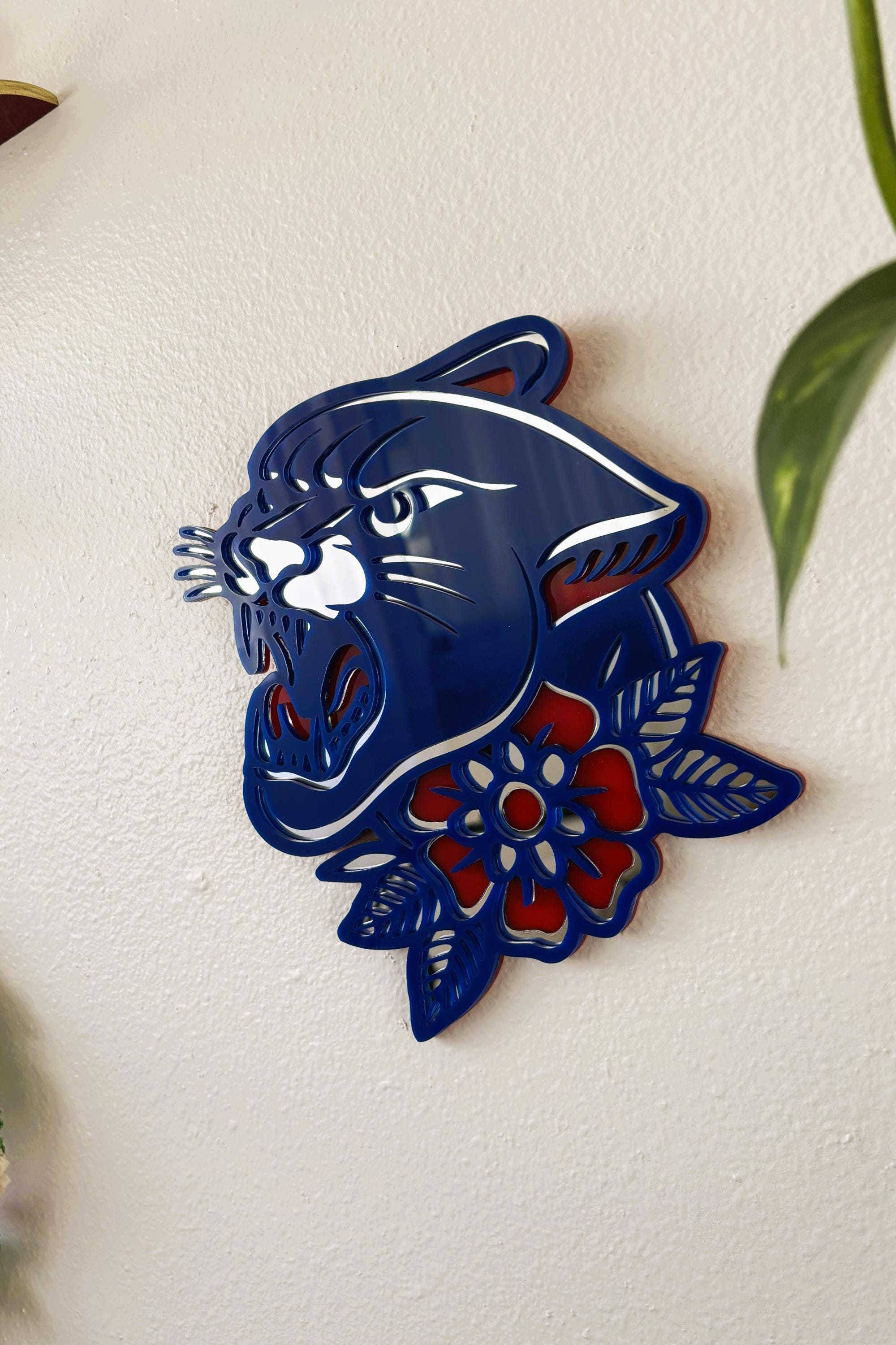 Decorative wall art of a blue panther head with floral patterns on a white wall.