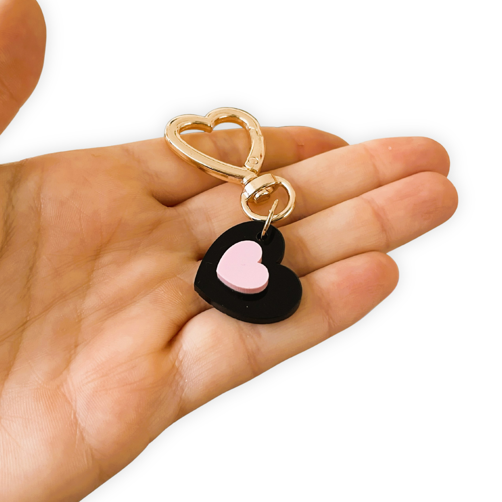 Heart-shaped keychain with gold ring held in a hand on a white background